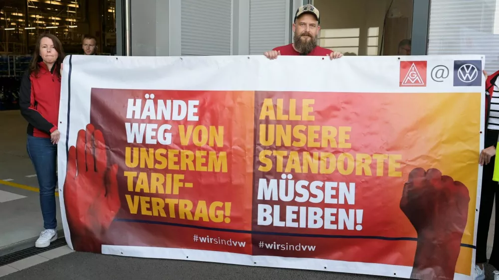 Protesters from German union IG Metall pose with a banner that reads, "Hands off our collective agreement", and "All our locations must remain", as German Economy Minister Robert Habeck visits a Volkswagen plant in Emden, Germany September 20, 2024. REUTERS/Fabian Bimmer