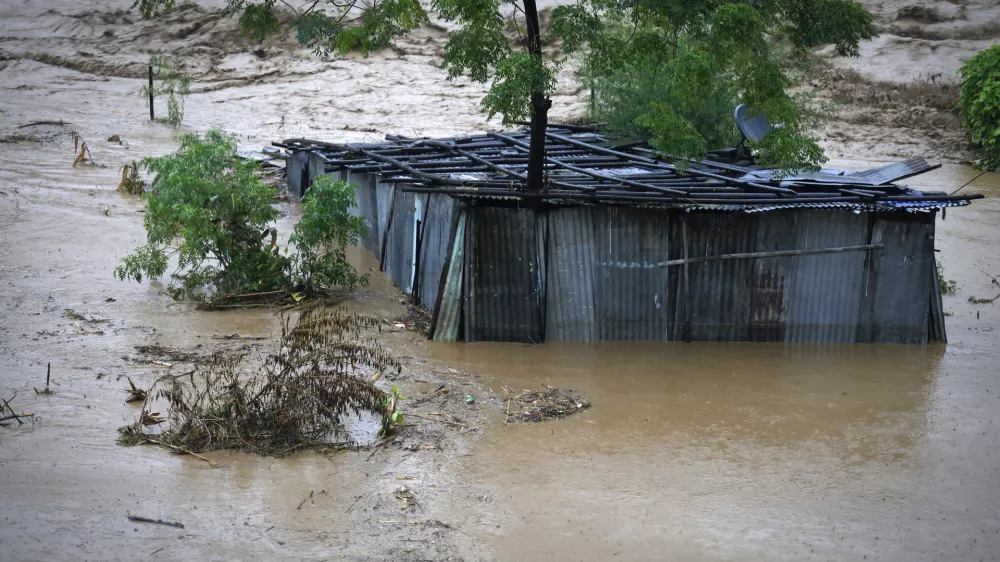 A tin shed lies partially submerged at the edge of the Bagmati River in spate after heavy rains in Kathmandu, Nepal, Saturday, Sept. 28, 2024. (AP Photo/Gopen Rai)