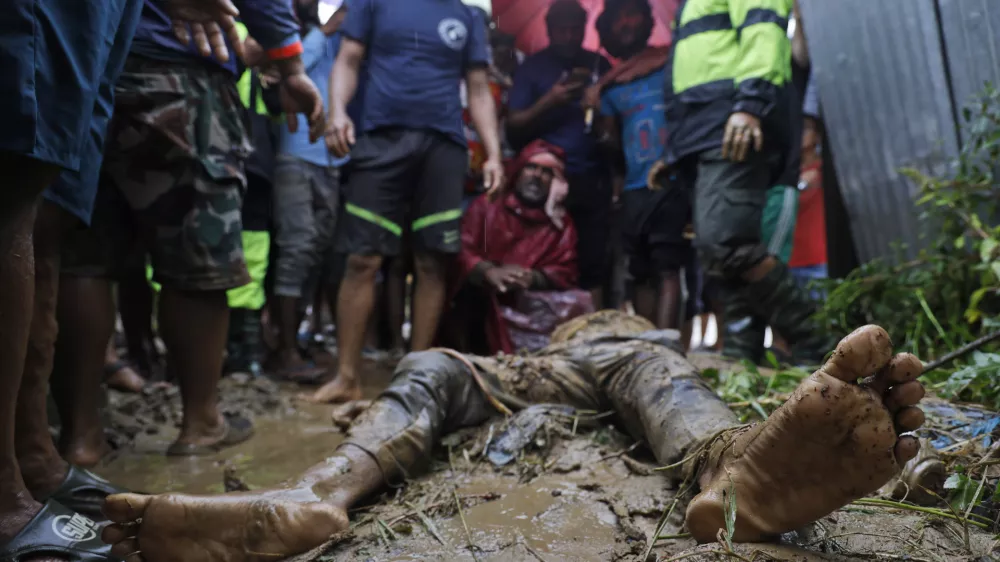 EDS NOTE: GRAPHIC CONTENT - People, including relatives, stand by the body of Nandu Sah, 34, a scrap dealer, who died after the shed he was sleeping under was flooded due to heavy rains, on the outskirts of Kathmandu, Nepal, Saturday, Sept. 28, 2024. (AP Photo/Gopen Rai)