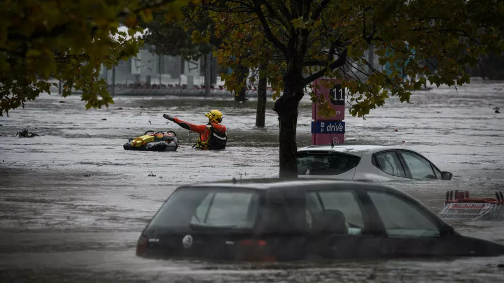 17 October 2024, France, Givors: Firefighters wade through the floodwaters, past partially flooded cars parked in a flooded shopping center. Photo: Jean-Philippe Ksiazek/AFP/dpa