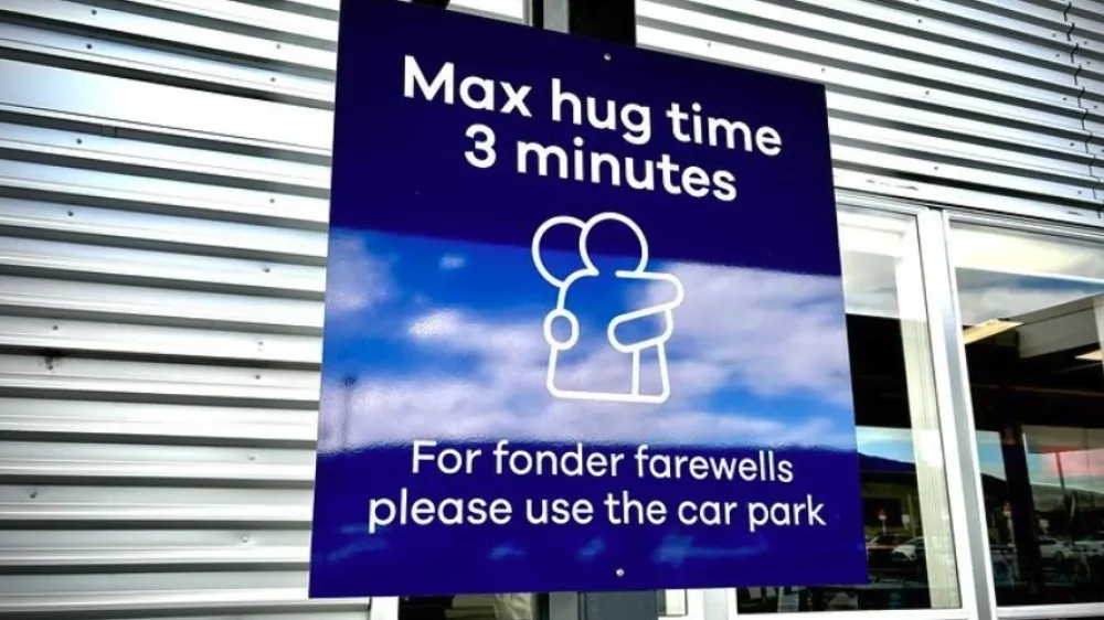 Napis o omejitvi objemanja na letali&scaron;ču Dunedin na Novi Zelandiji.