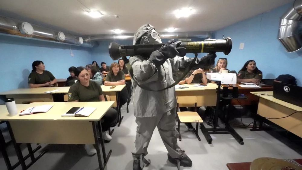 Ukrajinski vojaki v za&scaron;čitni obleki na usposabljanju za narodni upor v regiji Harkiv prikazujejo, kako se uporablja orožje. Foto: AP