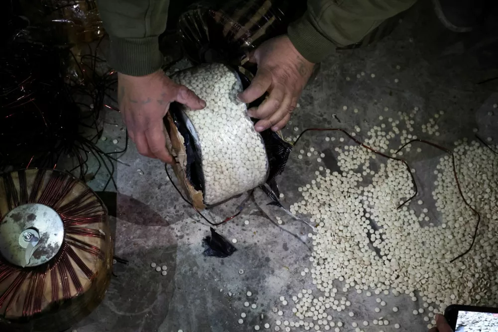 A fighter, loyal to Syria's new ruling administration, opens a box containing according to them, captagon pills, on the outskirts of Damascus, Syria December 12, 2024. REUTERS/Mohamed Azakir