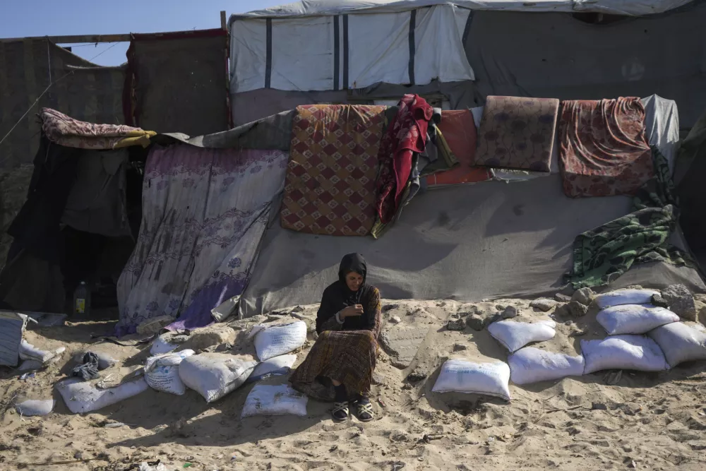 A woman sits outside a tent made locally from pieces of cloth and nylon, in a camp for internally displaced Palestinians at the beachfront in Deir al-Balah, central Gaza Strip, Friday, Dec. 27, 2024. (AP Photo/Abdel Kareem Hana)