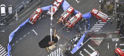 First responders try to rescue the driver of a truck that fell into a sinkhole on a street in Yashio, northeast of Tokyo, Tuesday, Jan. 28, 2025. (Kenichiro Kojima/Kyodo News via AP)