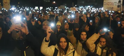 People hold up their mobile phone lights as tens of thousands gather for a protest over the collapse of a concrete canopy that killed 15 people more than two months ago, in Novi Sad, Serbia, Saturday, Feb. 1, 2025. (AP Photo/Darko Vojinovic)
