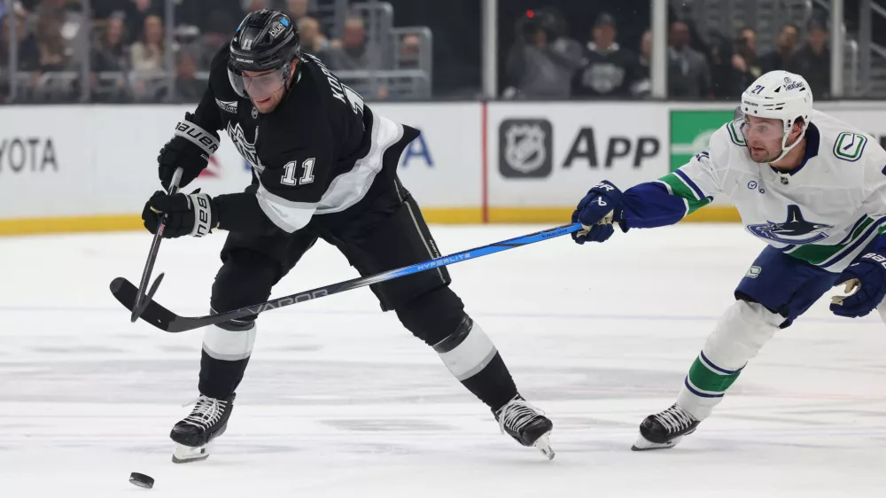 Feb 26, 2025; Los Angeles, California, USA; Los Angeles Kings center Anze Kopitar (11) skates against Vancouver Canucks left wing Nils Hoglander (21) during the second period at Crypto.com Arena. Mandatory Credit: Jason Parkhurst-Imagn Images