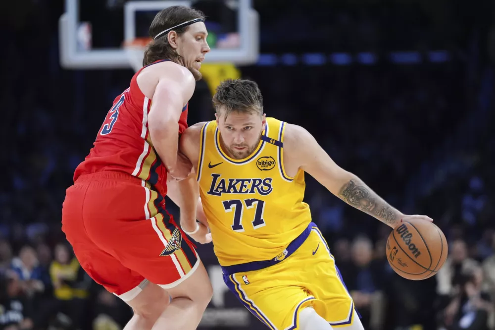 Los Angeles Lakers' Luka Doncic (77) is pressured by New Orleans Pelicans' Kelly Olynyk (13) during the second half of an NBA basketball game Tuesday, March 4, 2025, in Los Angeles. (AP Photo/Jae C. Hong)