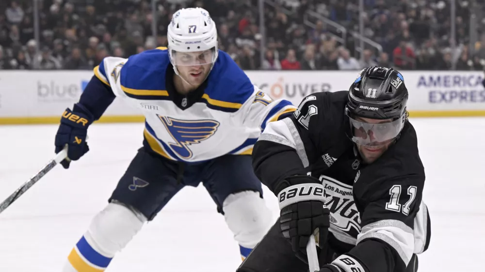 Mar 5, 2025; Los Angeles, California, USA; Los Angeles Kings center Anze Kopitar (11) reaches for the puck with St. Louis Blues defenseman Cam Fowler (17) defending during the second period at Crypto.com Arena. Mandatory Credit: Alex Gallardo-Imagn Images