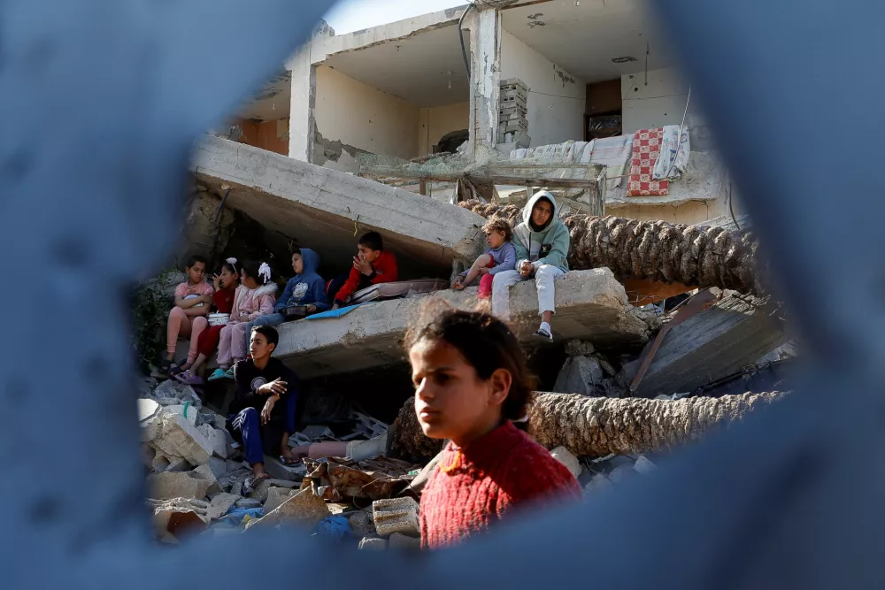 Palestinian children sit on rubble as they wait to receive food cooked by a charity kitchen, during the Muslim holy month of Ramadan, in Rafah, in the southern Gaza Strip, March 13, 2025. REUTERS/Hatem Khaled