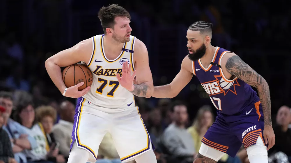 Mar 16, 2025; Los Angeles, California, USA; Los Angeles Lakers guard Luka Doncic (77) is defended by Phoenix Suns forward Cody Martin (17) in the second half at Crypto.com Arena. Mandatory Credit: Kirby Lee-Imagn Images