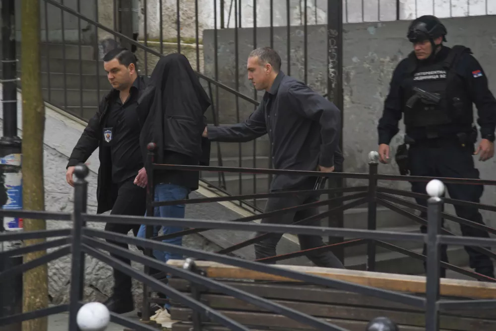 A suspect is escorted by police outside the Vladislav Ribnikar school in Belgrade, Serbia, Wednesday, May 3, 2023. Serbian police say a teenage boy opened fire at a school in central Belgrade, killing several people and injuring several more. (AP Photo)