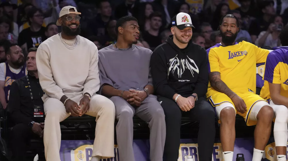 Los Angeles Lakers forward LeBron James, left, forward Rui Hachimura, second from left, guard Luka Doncic, second from right, and forward Markieff Morris sit on the bench during the first half of an NBA basketball game against the Milwaukee Bucks Thursday, March 20, 2025, in Los Angeles. (AP Photo/Mark J. Terrill)