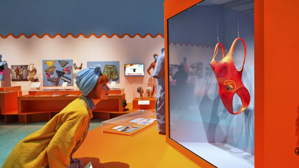 Guest curator Amber Butchart looks towards Pamela Anderson's Baywatch swimsuit on display at 'Splash! A century of Swimming and Style' an exhibition of swimwear and swim related items, at The Design Museum in London, Monday, March 24, 2025. (AP Photo/Kirsty Wigglesworth)