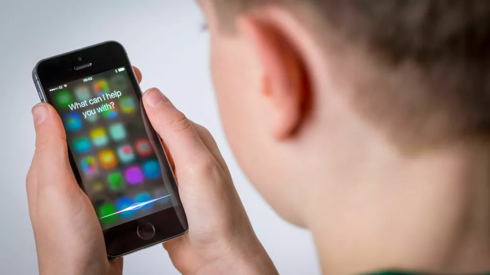 HN3525 A teenage boy using Siri on an iPhone