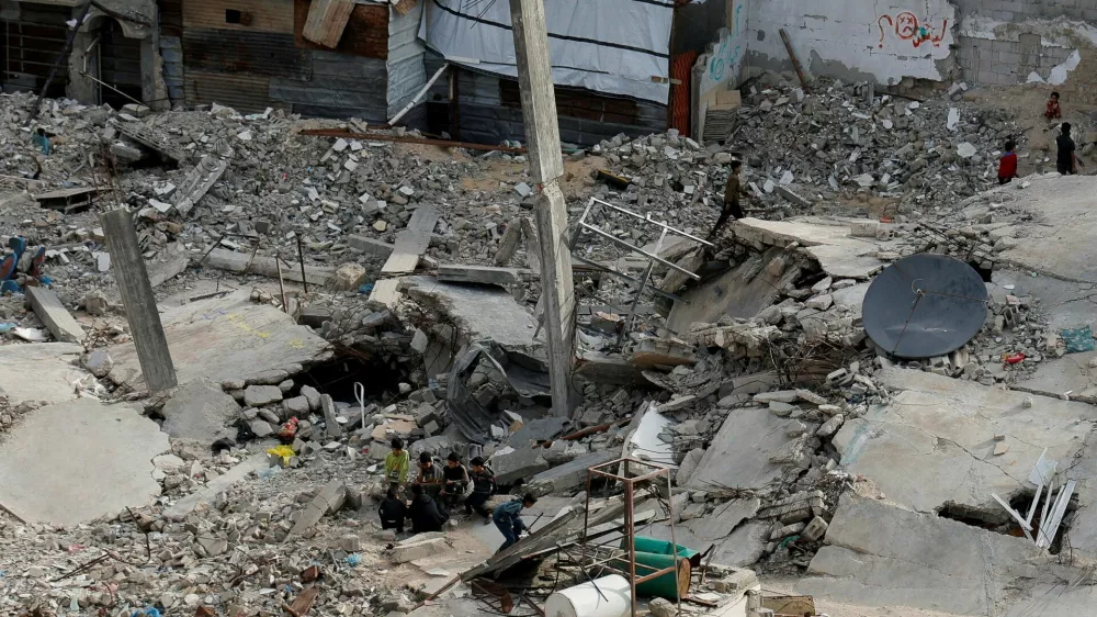 Palestinians sit amid rubble of houses, in Khan Younis in the southern Gaza Strip March 29, 2025. REUTERS/Hatem Khaled