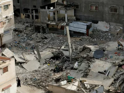 FILE PHOTO: A Palestinian woman walks near the rubble of houses, in Khan Younis in the southern Gaza Strip March 29, 2025. REUTERS/Hatem Khaled/File Photo