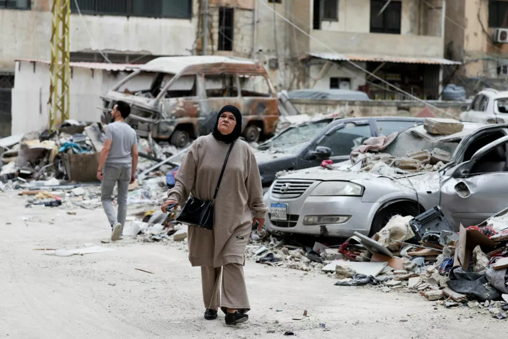 A woman walks past damaged vehicles in the aftermath of an Israeli airstrike, in Beirut, Lebanon April 1, 2025. REUTERS/Mohamed Azakir