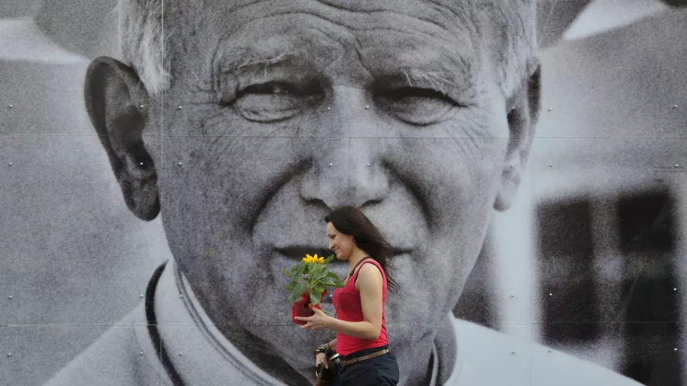 A Polish woman passes by a giant poster of the late Pope John Paul II in downtown Krakow, Poland, Thursday, April 28, 2011. An open-air photo exhibition in Krakow remembers Poland's most beloved and revered son, Pope John Paul II before his beatification ceremony in Rome on Sunday. (AP Photo/Bela Szandelszky)
