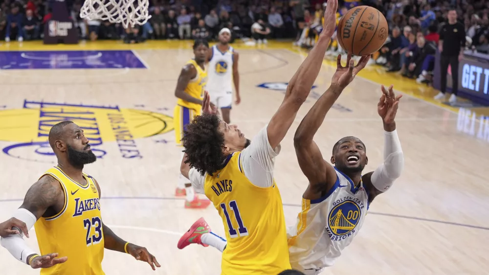 Golden State Warriors forward Jonathan Kuminga, right, shoots as Los Angeles Lakers center Jaxson Hayes, center, and forward LeBron James defend during the second half of an NBA basketball game Thursday, April 3, 2025, in Los Angeles. (AP Photo/Mark J. Terrill)