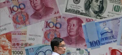 ﻿FILE - In this June 10, 2019, file photo, a man walks past a money exchange shop decorated with different banknotes at Central, a business district of Hong Kong. China's yuan fell Friday, Aug. 2, 2019, to its lowest level of the year against the dollar following U.S. President Donald Trump's threat of new tariffs on Chinese goods, coming close to breaking the politically sensitive level of seven to the U.S. currency. (AP Photo/Kin Cheung, File)