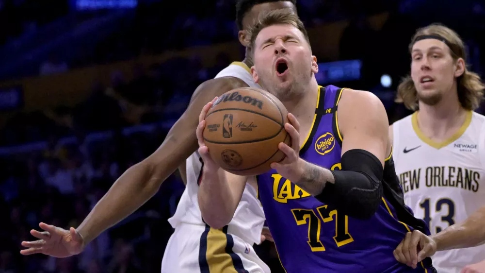 Apr 4, 2025; Los Angeles, California, USA; Los Angeles Lakers guard Luka Doncic (77) reacts after he was hit in the face driving past New Orleans Pelicans center Yves Missi (21) and forward Bruce Brown (00) in the first half at Crypto.com Arena. Mandatory Credit: Jayne Kamin-Oncea-Imagn Images