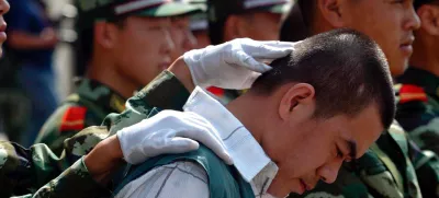 A Chinese paramilitary officer keeps the head of a drug dealer bowed during a public sentencing to mark International Day against Drug Abuse and Illicit Drug Trafficking in Hangzhou, eastern China's Zhejiang province, Monday, June 26, 2006. Chinese drug control officials said Thursday their yearlong war on drugs has severely squeezed heroin supplies from the Golden Triangle. Officials also announced the arrest of some 46,000 drug suspects and the seizure of some 6.9 tons of heroin last year. During the trial in Hangzhou, 20 drug dealers were sentenced today with three given the death penalty and executed soon after. (AP Photo) ** CHINA OUT **