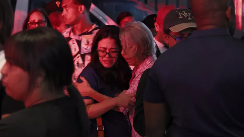 Relatives of missing people embrace while waiting at the National Institute of Forensic Pathology after the roof collapsed at Jet Set nightclub during a merengue concert in Santo Domingo, Dominican Republic, Tuesday, April 8, 2025. (AP Photo/Ricardo Hernandez)