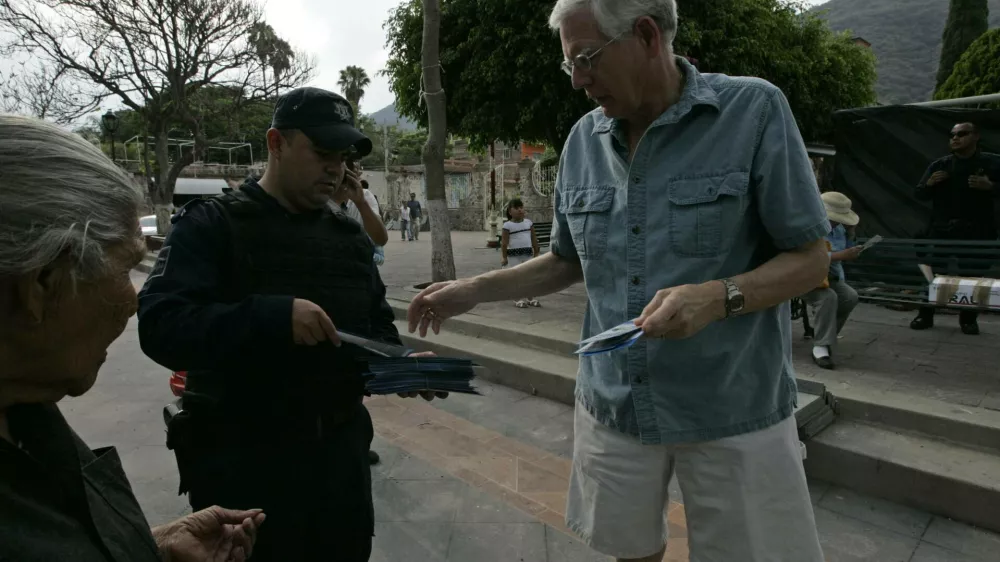 A policeman hands out a leaflet with security information to a foreign resident in the town of Ajijic, in the Mexican State of Jalisco, May 16, 2012. About 400 U.S. and Canadian citizens gathered on Wednesday to meet with officials of the municipal police to demand for more security. Ajijic, on the shore of Chapala lake, is one of the populations with the highest number of foreigners residing in Mexico and has been plagued by kidnappings and vendettas between rival groups of drug trafficking in the past months, local media reported. REUTERS/Alejandro Acosta (MEXICO - Tags: CIVIL UNREST SOCIETY CRIME LAW)