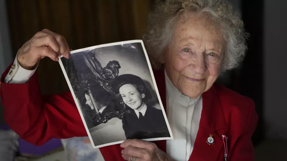 Dorothea Barron who was a serving Wren at the time of D-Day, holds up a photograph of herself in uniform during WWII, at her home near Sawbridgeworth, in England, Tuesday, May 7, 2024. D-Day, took place on June 6, 1944, the invasion of the beaches at Normandy in France by Allied forces during World War II. (AP Photo/Kirsty Wigglesworth)