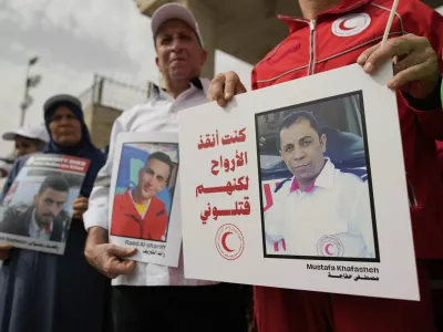 Paramedics from the Palestine Red Crescent Society, PRCS, one carrying a poster that reads "I was saving lives but they killed me," hold signs to honor members of medical missions who lost their lives while carrying out their humanitarian duty, in front of their headquarters in the West Bank city of Ramallah, Wednesday, April 23, 2025. (AP Photo/Nasser Nasser)