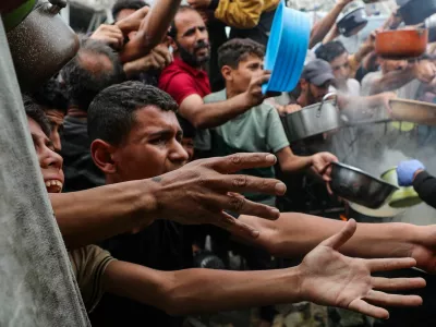 Palestinians wait to receive food cooked by a charity kitchen, in Beit Lahia, northern Gaza Strip, April 24, 2025. REUTERS/Mahmoud Issa