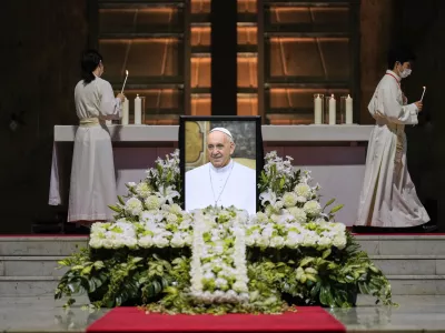 Priests prepare for a memorial Mass for the late Pope Francis near his portrait at St. Mary's Cathedral in Tokyo, Sunday, April 27, 2025. (AP Photo/Hiro Komae, Pool)
