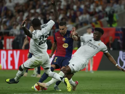 Barcelona's Ferran Torres, center, is challenged by Real Madrid's Antonio Rudiger, left, and Real Madrid's Aurelien Tchouameni during the Spanish Copa del Rey final soccer match between Barcelona and Real Madrid at Estadio de La Cartuja stadium in Seville, Spain, Saturday, April 26, 2025. (AP Photo/Joan Monfort)