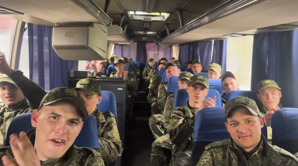In this photo taken from video distributed by Russian Defense Ministry Press Service on Tuesday, May 6, 2025, a group of Russian soldiers applaud as they sit in a bus after being released in a prisoners swap between Russia and Ukraine, at the Ukraine-Belarusian boarder. (Russian Defense Ministry Press Service via AP)