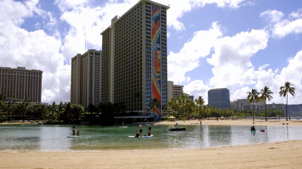 FILE - People swim in the lagoon in front of the Hilton Hawaiian Village resort in Honolulu on Saturday, Sept. 4, 2021. (AP Photo/Caleb Jones, File)