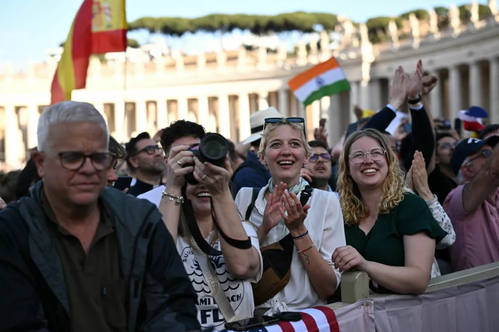 People react as white smoke rises from the chimney on the Sistine Chapel, indicating that a new pope has been elected at the Vatican, May 8, 2025.  REUTERS/DYLAN MARTINEZ