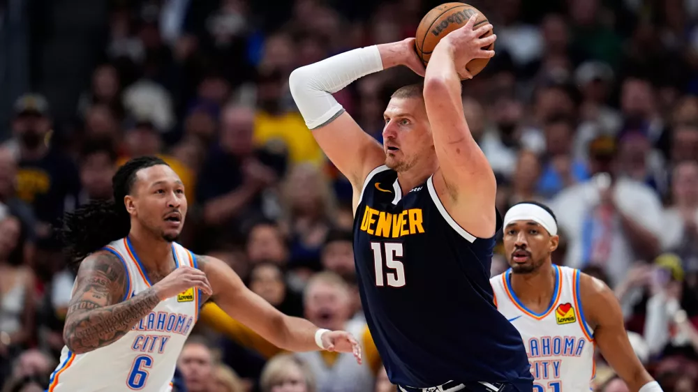 Denver Nuggets center Nikola Jokic, center, looks to pass the ball as Oklahoma City Thunder forward Jaylin Williams, left, and guard Aaron Wiggins defend in the second half of Game 4 in the Western Conference semifinals of the NBA basketball playoffs Sunday, May 11, 2025, in Denver. (AP Photo/David Zalubowski)