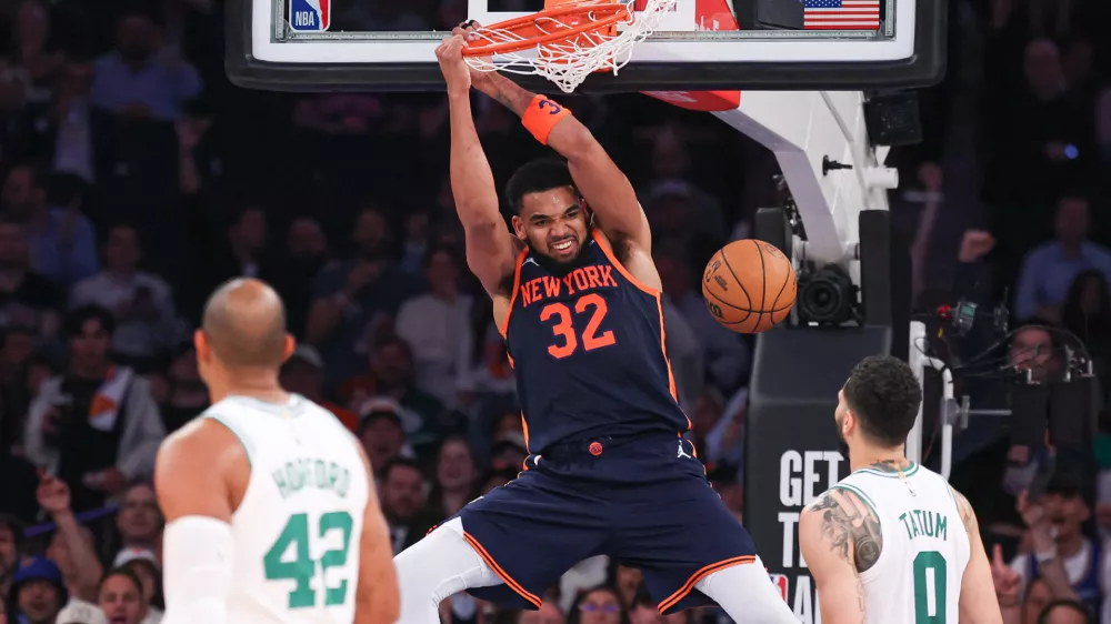 May 12, 2025; New York, New York, USA; New York Knicks center Karl-Anthony Towns (32) dunks the ball in the second half during game four of the second round for the 2025 NBA Playoffs in front of Boston Celtics forward Jayson Tatum (0) at Madison Square Garden. Mandatory Credit: Vincent Carchietta-Imagn Images