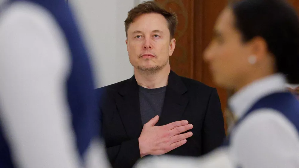 Tesla CEO Elon Musk holds his hand on his heart as the U.S. national anthem is played at a state dinner hosted by Qatar's Emir Tamim bin Hamad Al Thani during a visit by U.S. President Donald Trump, at Lusail Palace in Lusail, Qatar, May 14, 2025. REUTERS/Brian Snyder