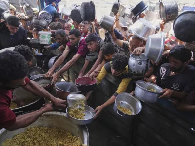 Palestinians struggle to get donated food at a community kitchen in Khan Younis, Gaza Strip, Friday, May 16, 2025. (AP Photo/Abdel Kareem Hana)