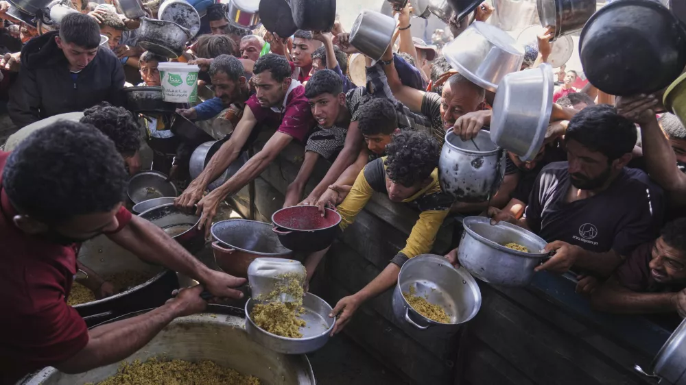 Palestinians struggle to get donated food at a community kitchen in Khan Younis, Gaza Strip, Friday, May 16, 2025. (AP Photo/Abdel Kareem Hana)