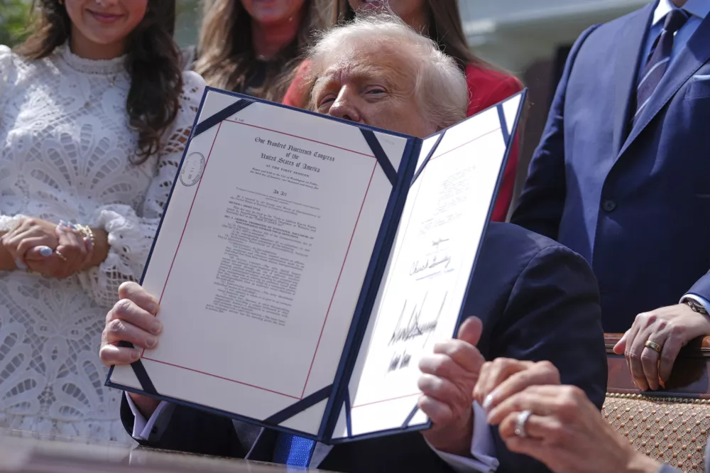 President Donald Trump holds up a bill for the "Take it Down Act" that he and first lady Melania Trump signed in the Rose Garden of the White House, Monday, May 19, 2025, in Washington. (AP Photo/Evan Vucci)