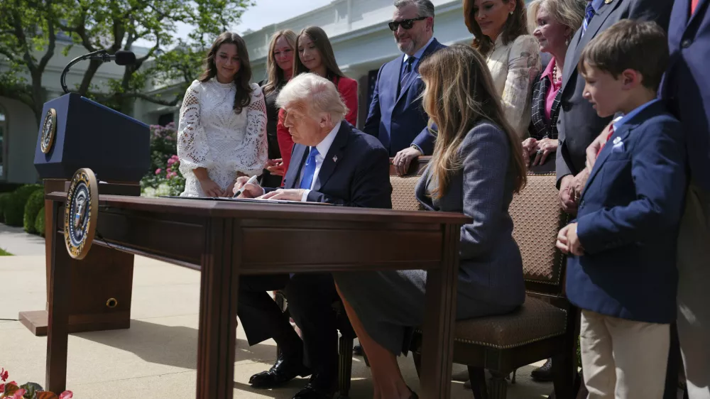President Donald Trump signs a bill for the "Take it Down Act" as first lady Melania Trump, seated right, Rep. Maria Salazar R-Fla., standing from fourth right, Sen. Ted Cruz, R-Texas, background center, and others watch as Trump in the Rose Garden of the White House, Monday, May 19, 2025, in Washington. (AP Photo/Evan Vucci)