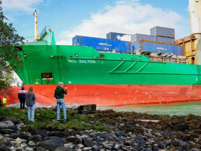 People stand near a container ship, which almost hit a house, in Trondheim, Norway, May 22, 2025. NTB/Jan Langhaug/via REUTERS  ATTENTION EDITORS - THIS IMAGE WAS PROVIDED BY A THIRD PARTY. NORWAY OUT. NO COMMERCIAL OR EDITORIAL SALES IN NORWAY.
