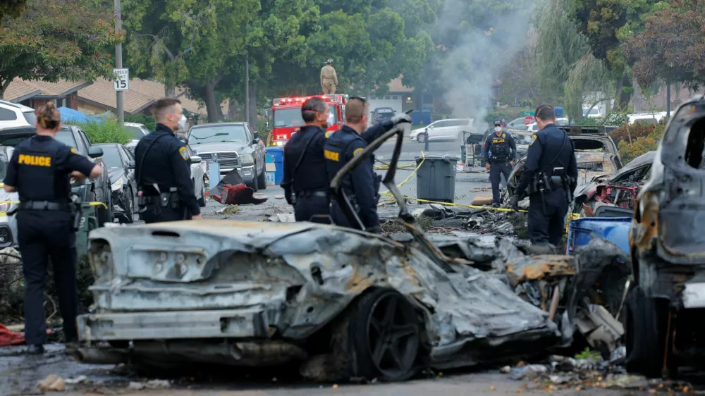 Emergency personnel work at the crash scene on a street, after a small civilian aircraft went down in a military neighborhood in San Diego, California, U.S. May 22, 2025. REUTERS/Mike Blake