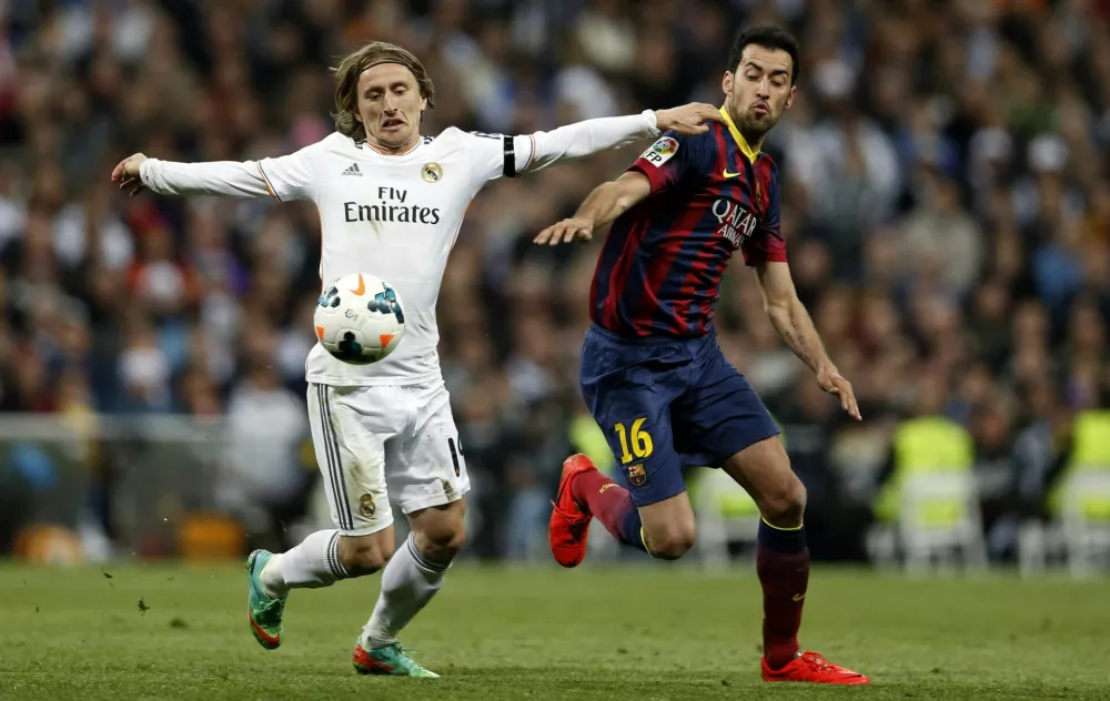 ﻿Real Madrid's Luka Modric (L) fights for the ball against Barcelona's Sergio Busquets during La Liga's second 'classic' soccer match of the season at Santiago Bernabeu stadium in Madrid March 23, 2014. REUTERS/stringer (SPAIN - Tags: SPORT SOCCER)