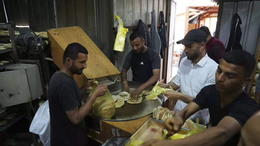 Palestinians bake bread after the World Food Program was able to bring in flour for the first time in over a month as Israel allowed some aid to enter the Gaza Strip, in Deir al-Balah, Gaza Strip, Thursday, May 22, 2025. (AP Photo/Abdel Kareem Hana)