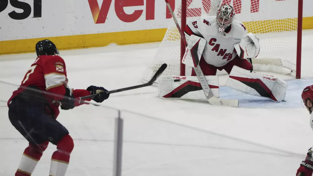 Florida Panthers defenseman Niko Mikkola, left, shoots to score a goal against Carolina Hurricanes goaltender Pyotr Kochetkov, right, during the third period in Game 3 of the NHL hockey Stanley Cup Eastern Conference finals Saturday, May 24, 2025, in Sunrise, Fla. (AP Photo/Lynne Sladky)