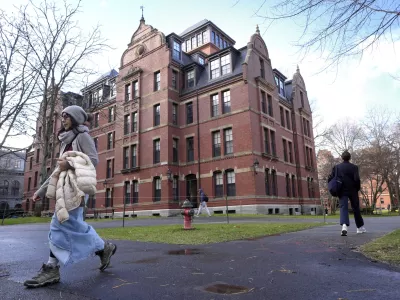 FILE - People walk between buildings, Dec. 17, 2024, on the campus of Harvard University in Cambridge, Mass. (AP Photo/Steven Senne, File)